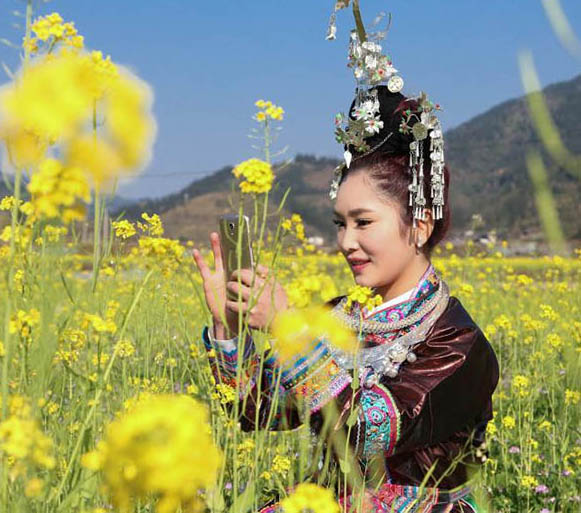 トン族の村に春來たる、花と戯むる村の女性たち