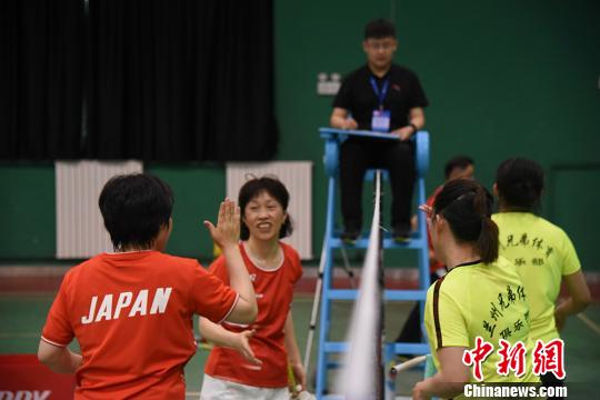 中日両國のバドミントン愛好者が試合後にハイタッチを交わす様子（撮影?鍾欣）。