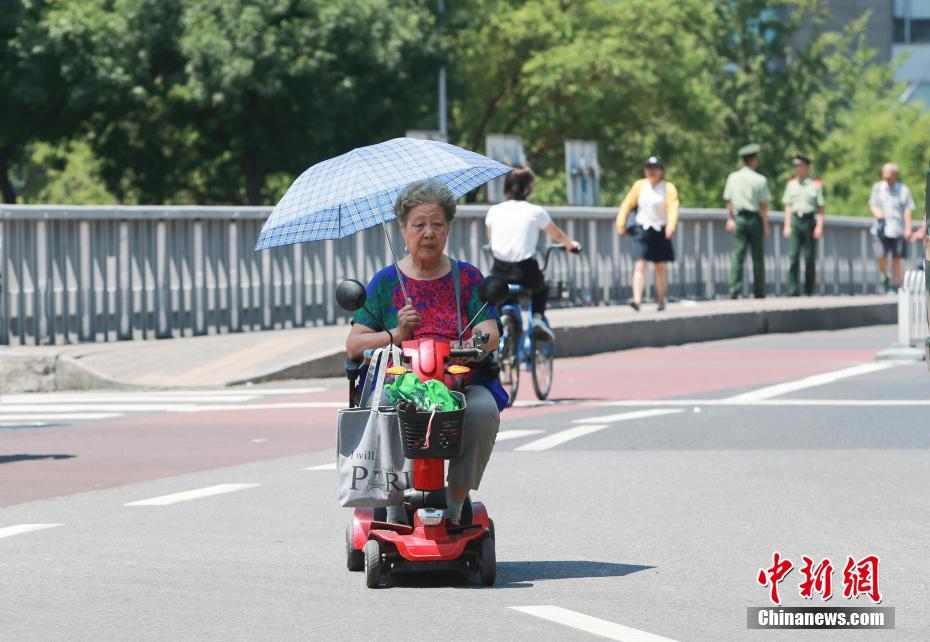 高溫が続く猛暑の北京　様々な日焼け対策で外出する市民