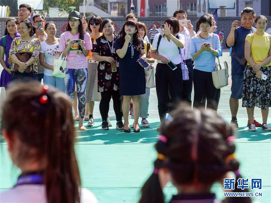 9月1日、北京市東城區燈市口小學?燈市口キャンパスで行われた入學式終了後の記念撮影をする新一年生の橫で寫真を撮る保護者ら。中には、子供にポーズのとりかたを教える保護者の姿も (撮影?沈伯韓)。