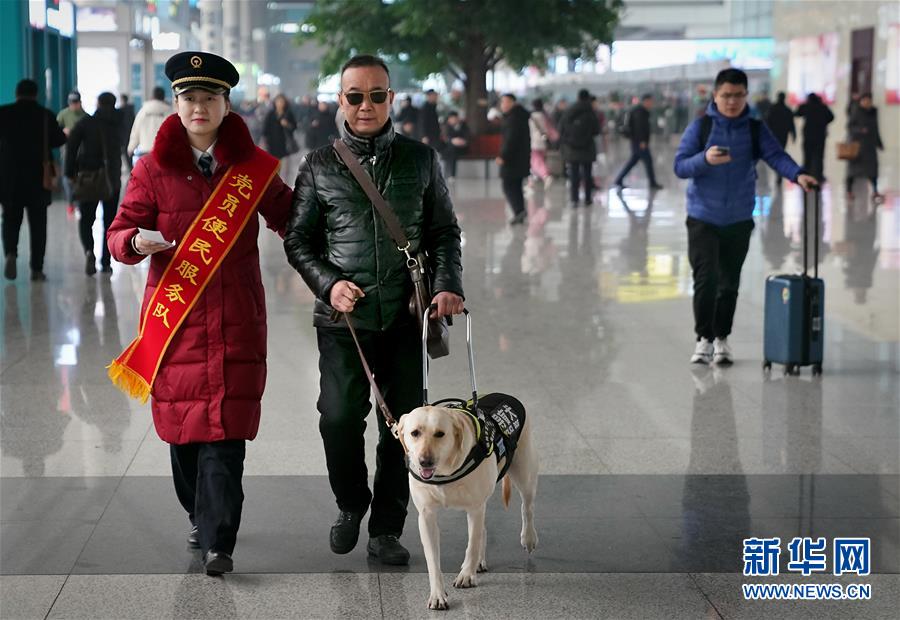 目の不自由な乗客の靳さんと盲導犬の「小七」を駅構內の待合室まで案內する鄭州東駅のスタッフ（1月14日に撮影?李安）。