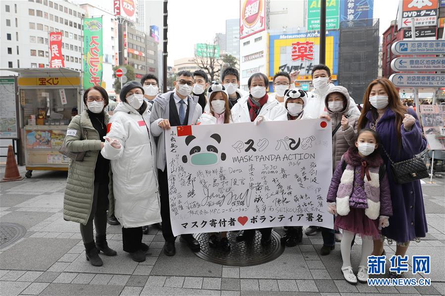 2月29日、日本の東京?池袋駅前で道行く人々にマスクを配った後記念撮影し、中國と日本の感染拡大防止にエールを送る「マスクパンダアクション」のボランティアたち（撮影?杜瀟逸）。