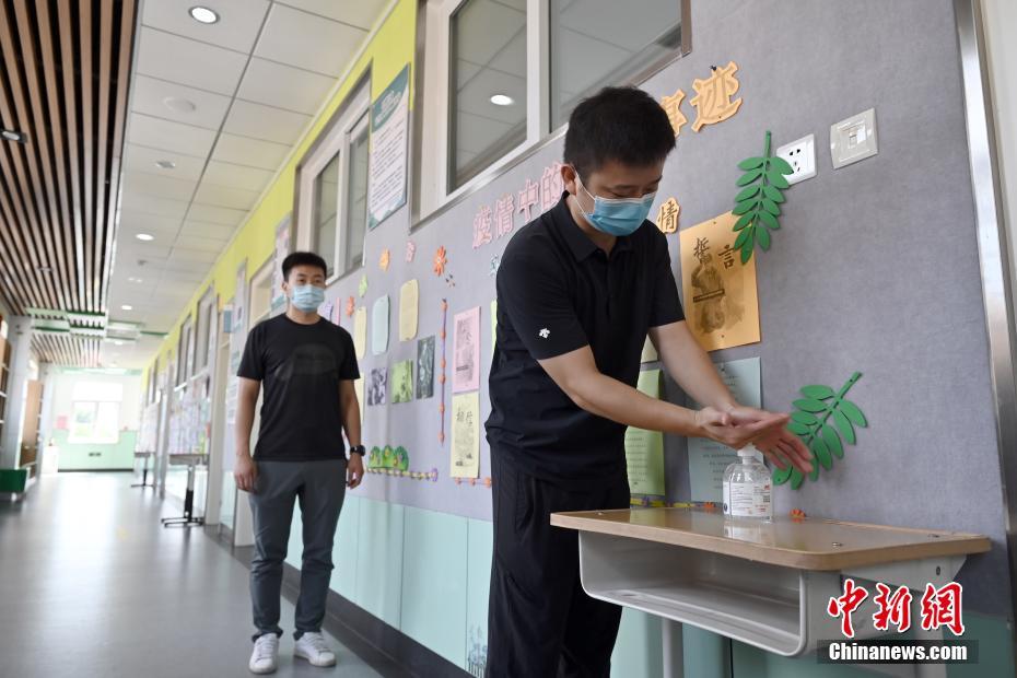 8月24日、北京教育學院附屬豊臺実験學校で、教室に入る前に手の消毒を行う教職員。同校の全教室の入口には、新學期開始後に生徒が使用できるように、消毒ジェルなどの防疫用品が設置されている（撮影?張興龍）。