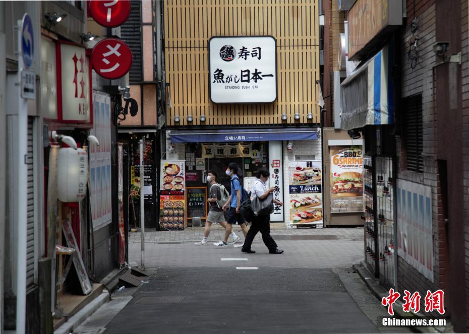 東京で、すし屋の前を通り過ぎる市民（撮影?呂少威）。