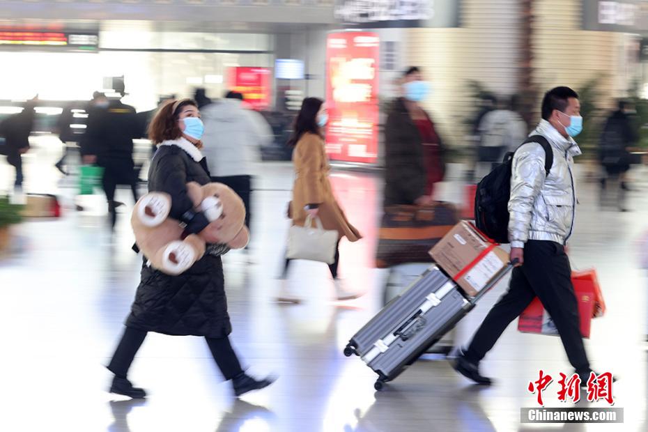 クマのぬいぐるみを抱えたり、キャリーカートの荷物を手に南京鉄道駅構內に移動する乗客（撮影?泱波）。