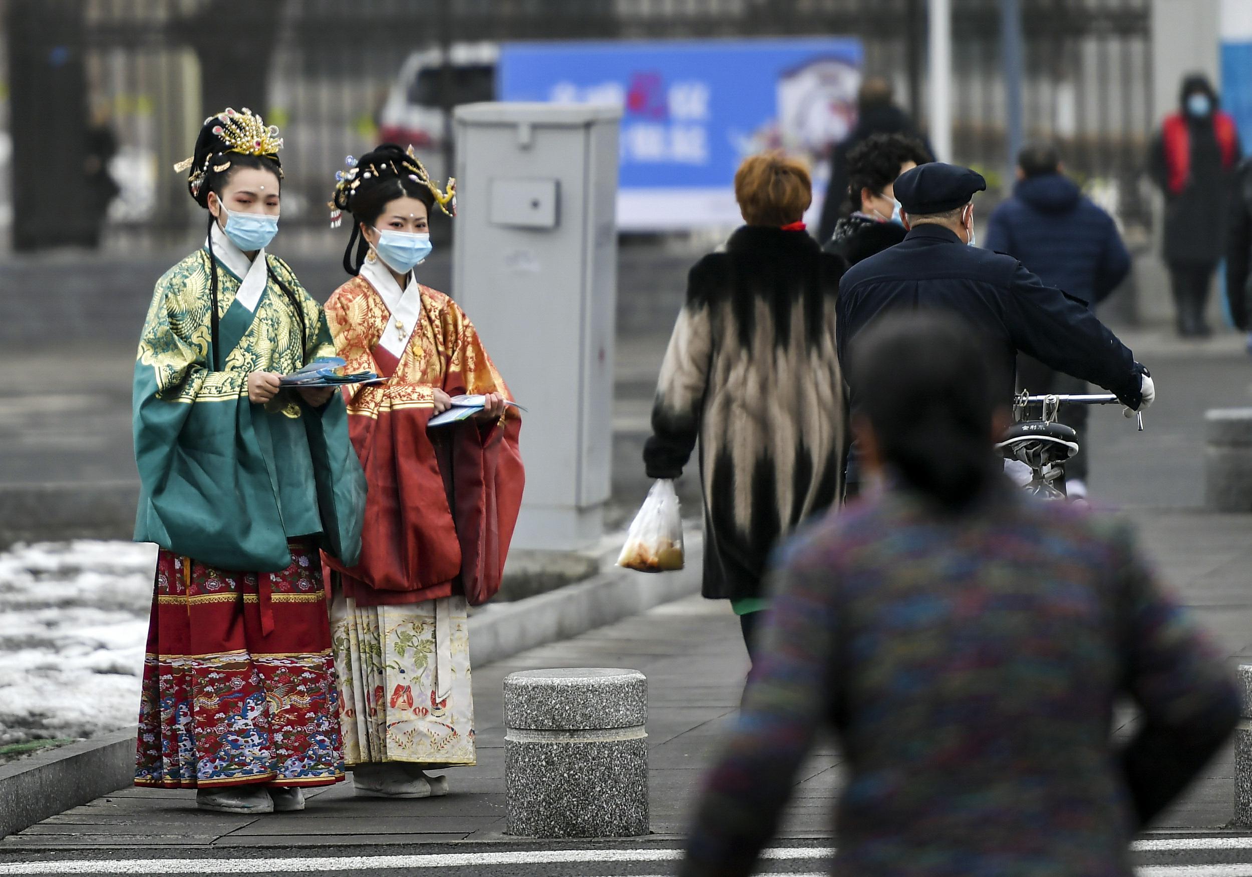 3月10日、新疆ウルムチ市ハイテク區（新市區）の北京路で、交通ルールやマナーを守った外出を通行者に呼びかける、漢服姿のボランティア（寫真著作権はCFP視覚中國が所有のため転載禁止）。