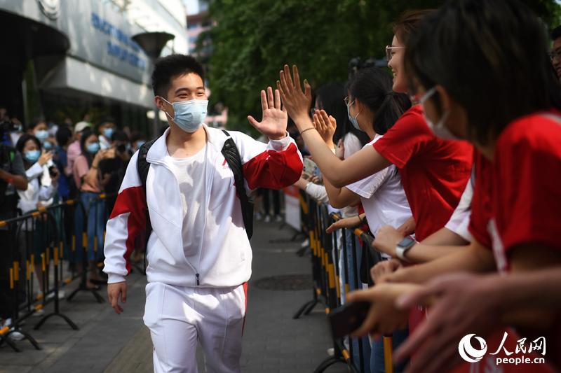 6月7日、北京人民大學附屬中學（中高一貫校）の入口で、順序良く試験會場に入る受験生とハイタッチを交わす見送りの人々（撮影?翁奇羽）。