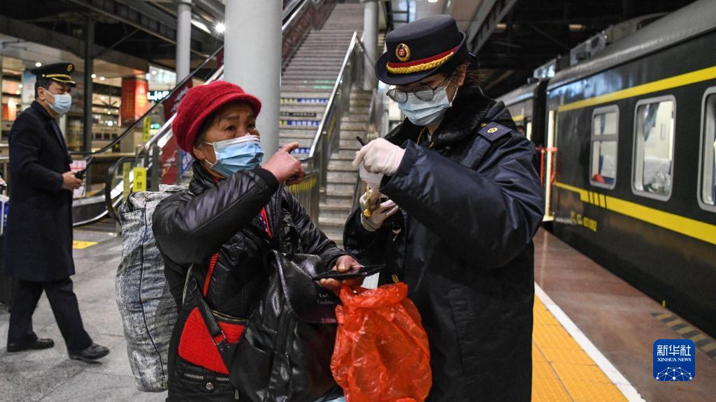 広西壯（チワン）族自治區柳州列車駅で、高齢の乗客からの質問に対応し、スムーズに乗車できるよう手伝う、旅客輸送擔當職員の龍澤飛さん（1月24日撮影?張愛林）。