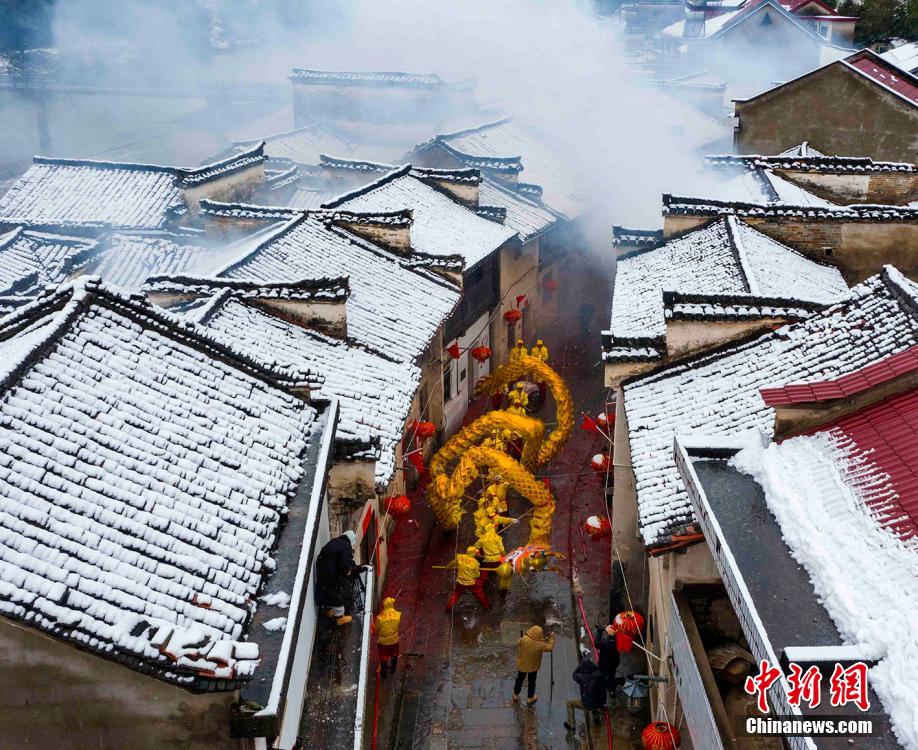 安徽省寧國市胡楽鎮で、雪が積もった歴史ある通りを胡楽司龍燈チームが元宵節の龍の舞いを披露しながらねり歩く様子（2月14日撮影?李暁紅）。