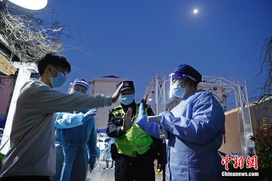 虹橋空港新村で15日、警察官に率いられ、PCR検體採取前の検溫を受ける住民（撮影?殷立勤）。