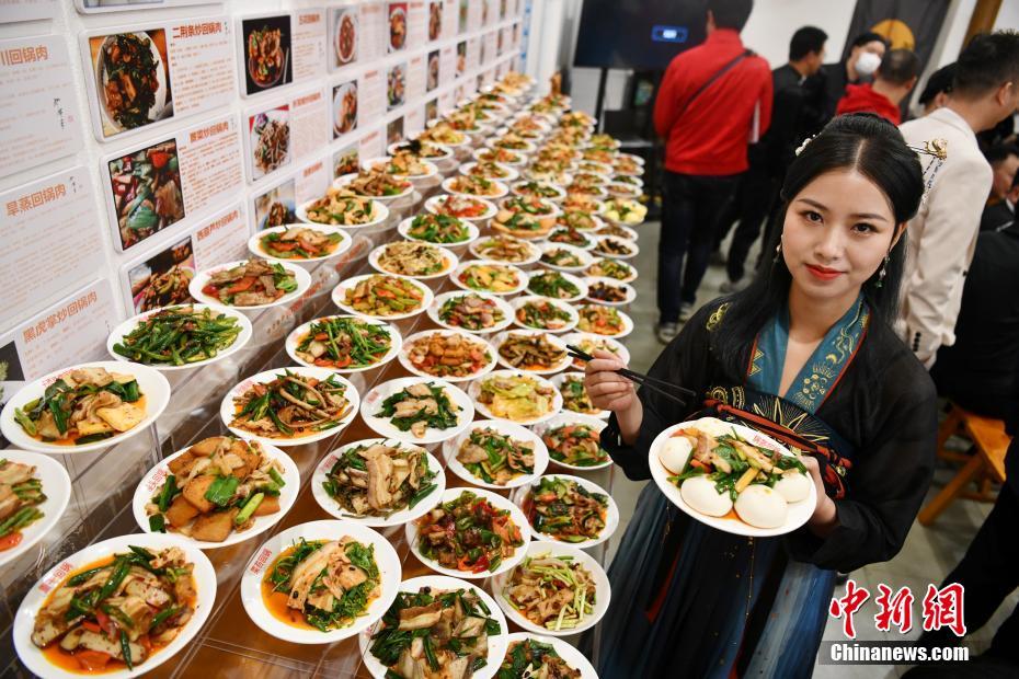 自らが作った「ニンニクの芽回鍋肉」を見(jiàn)せる、「108種類(lèi)の回鍋肉メニュー」を企畫(huà)した羅程丹さん（撮影?張浪）。