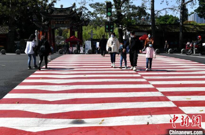 紅白縞模様の橫斷歩道を渡る市民（撮影?呂明）。