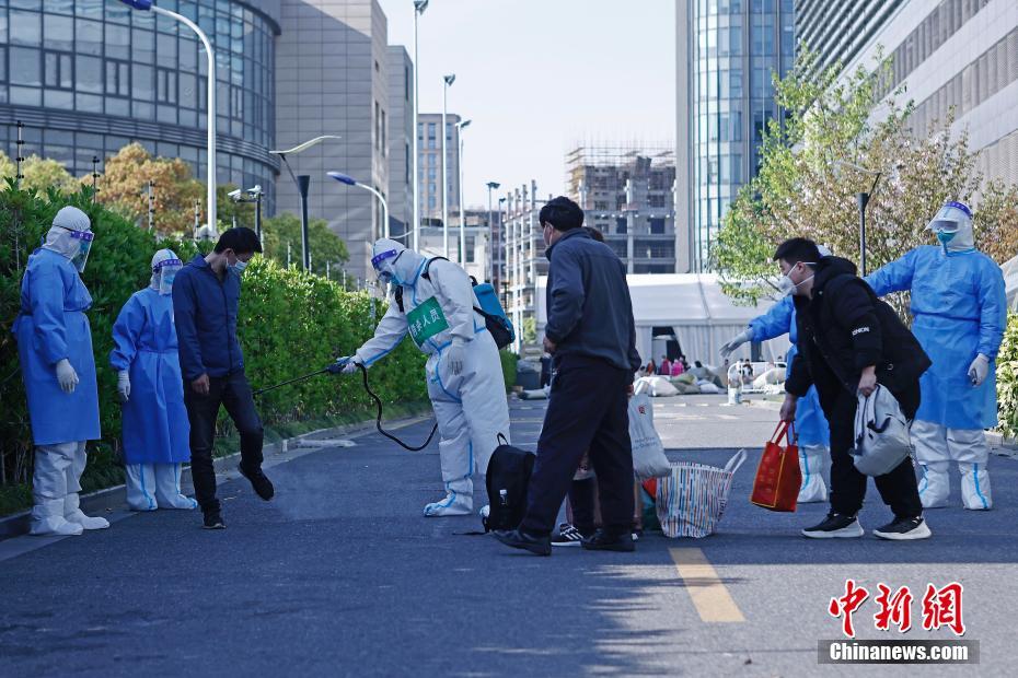 4月9日、上海市普陀區の上海跨國采購會展センターに設けられた方艙醫院（臨時醫療施設）で、各自荷物を持ち、醫院を出て自宅に戻るための車両に乗る準備をする第一陣回復患者の4人（撮影?殷立勤）。