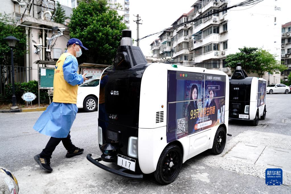 4月25日、コミュニティ入口で配送物を無人配送車に入れる上海市楊浦區(qū)長海路街道（エリア）浣紗小區(qū)（コミュニティ）の黨員ボランティア（撮影?張建松）。