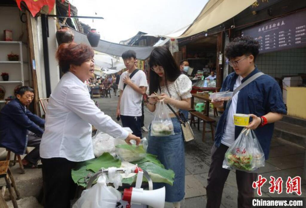 屋臺で餅菓子「麻糍」を購入するマカオ出身の學生?程芊慧さん（寫真一番右）と同級生（撮影?董易鑫）。