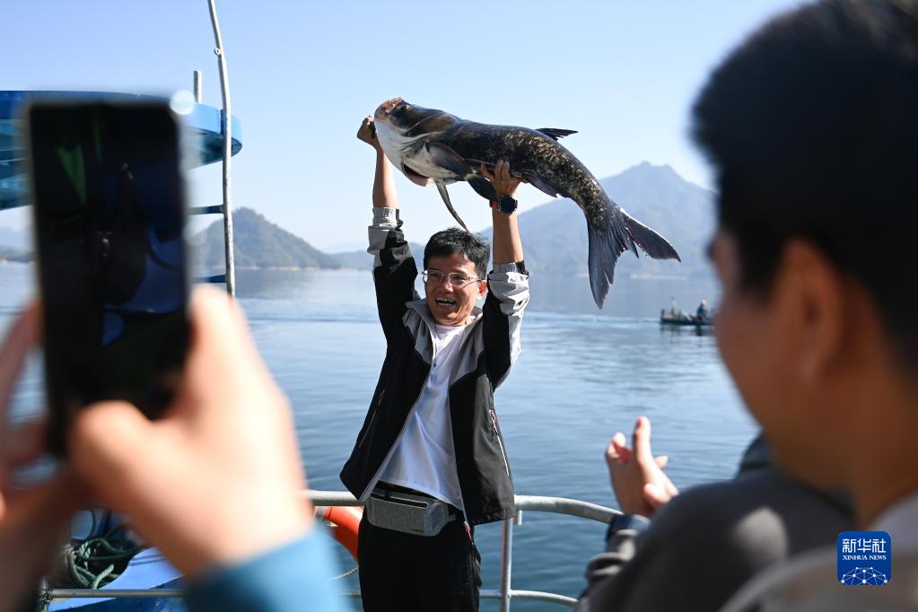 浙江省杭州市淳安県千島湖の黃山尖水域で、捕獲したばかりの「魚の王様」を両手で掲げる観光客（10月22日撮影?黃宗治）。