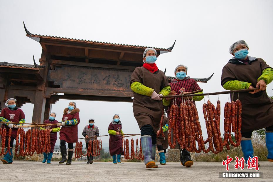 出來上がったばかりの腸詰めを乾燥場まで運ぶ村人たち（撮影?冉孟軍）。