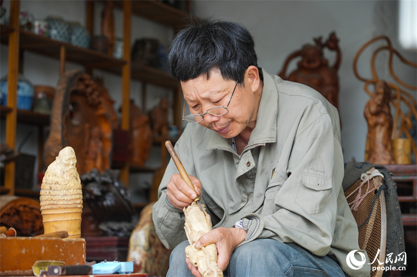 「根彫」の作品を制作する江西省級無形文化遺産「根彫」の代表性伝承人?劉四喜さん（撮影?孔文進）。