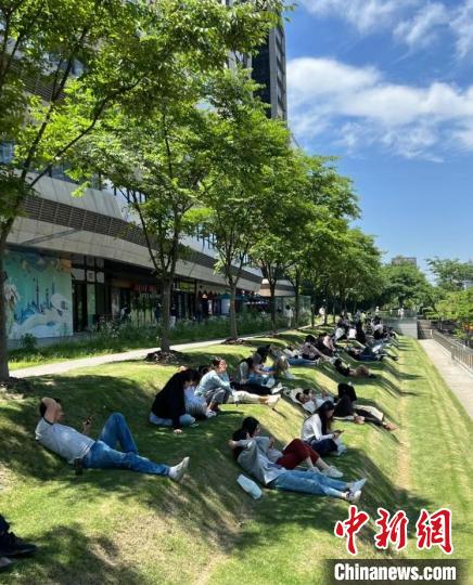 正午に上海市徐匯區の地下鉄?雲錦路駅付近の芝生の上で寢転ぶ若者たち（寫真提供?取材対応者）。