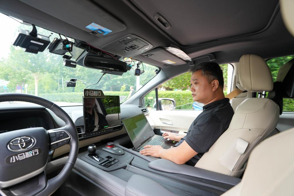 道路を走る自動運転テスト車両內で車載機器の路上試験をする王偉さん（6月19日撮影）。