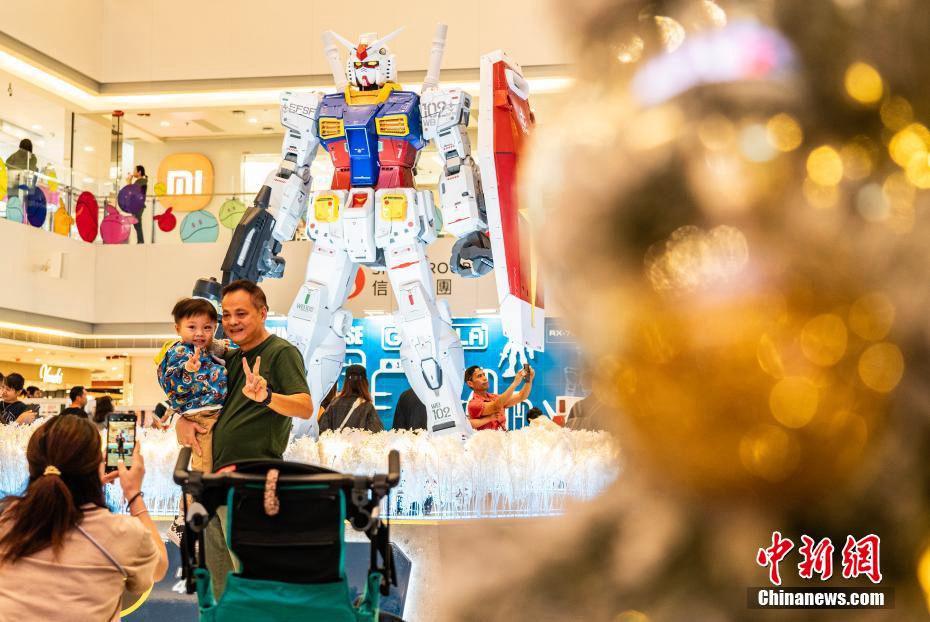 高さ3メートルの初代ガンダムRX-78-2の立像の前で記念撮影する市民や観光客（撮影?侯宇）。